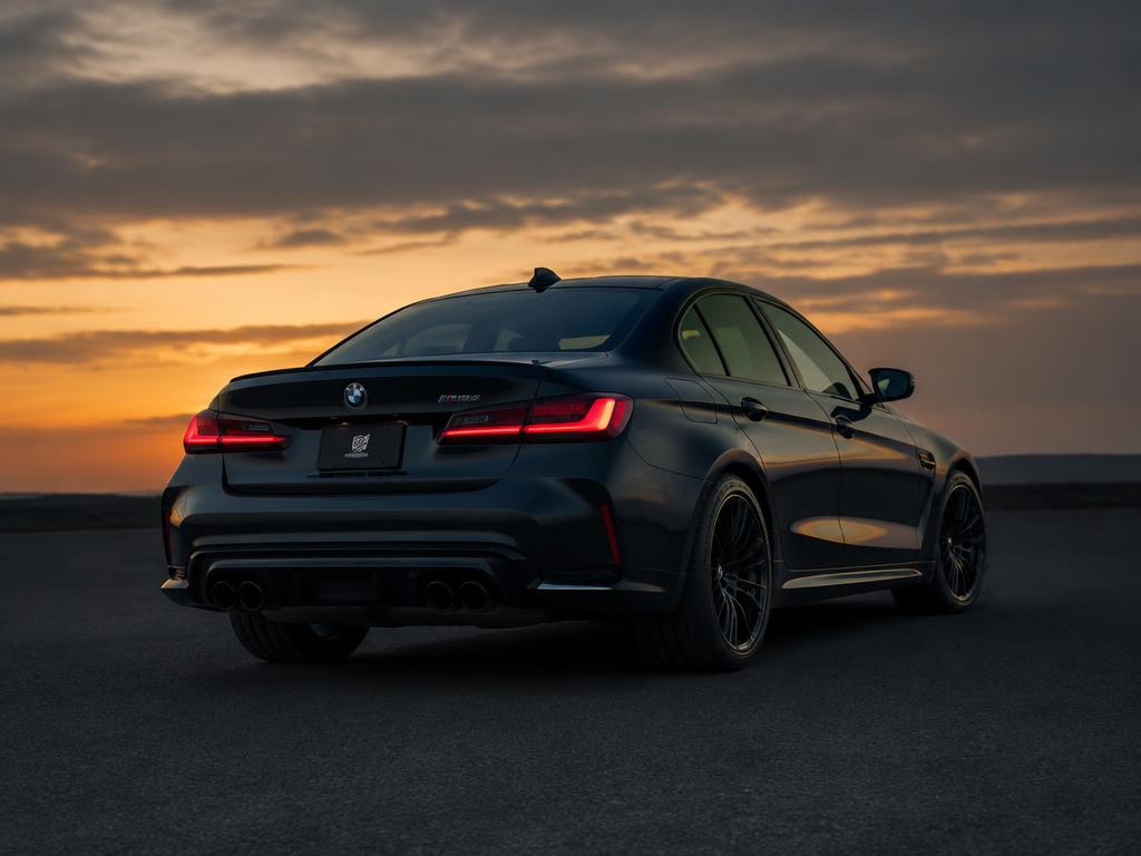 Rear three-quarter photograph of a dark sports sedan at dusk